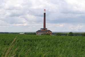 Výhledna továrnu s komínem přes pole u obce Zápy a Lázně Toušeň
